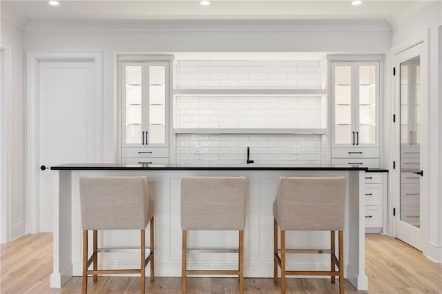 kitchen featuring white cabinets, a kitchen bar, and light wood-type flooring