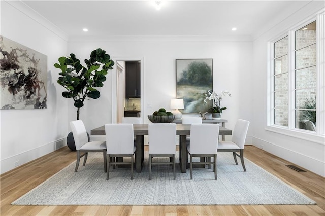 dining area with wood-type flooring and ornamental molding