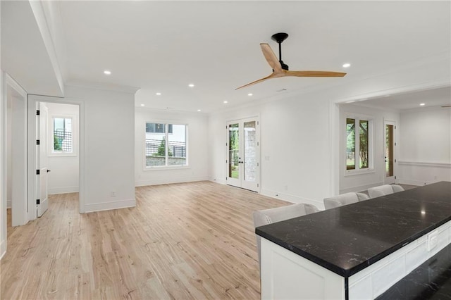 unfurnished living room with ceiling fan, crown molding, a wealth of natural light, and light hardwood / wood-style flooring