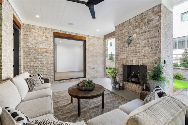 living room featuring an outdoor brick fireplace, ceiling fan, and brick wall