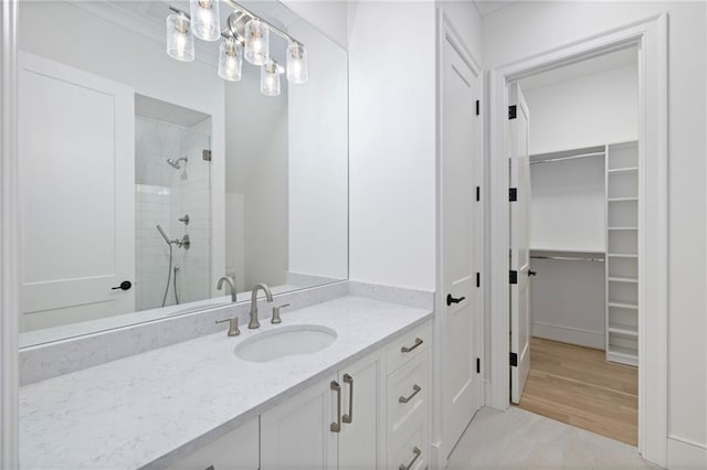 bathroom featuring vanity, a tile shower, and ornamental molding