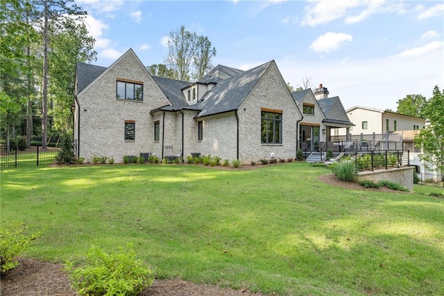 rear view of house with a wooden deck and a yard