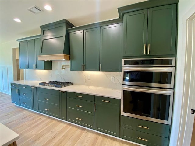 9224 Waldrip Rd, Gainesville, GA 30506 - kitchen with green cabinets, premium range hood, appliances with stainless steel finishes, light wood-style floors, and backsplash