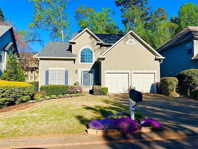 traditional-style house featuring stucco siding, a shingled roof, a front yard, a garage, and driveway