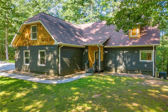 view of front of home with central air condition unit, roof with shingles, and a front yard