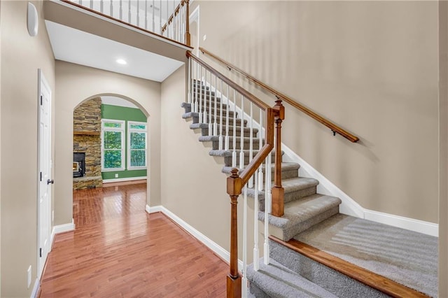 stairs with arched walkways, baseboards, and wood finished floors