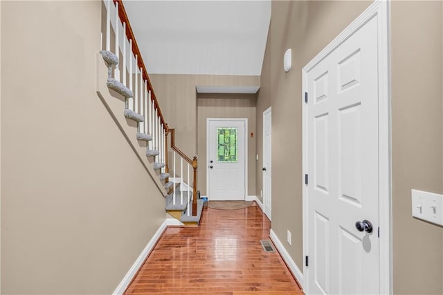 doorway to outside with baseboards, light wood-type flooring, and stairs