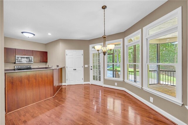 kitchen featuring hanging light fixtures, baseboards, a notable chandelier, light wood-style floors, and stainless steel appliances