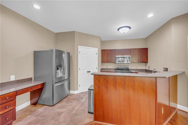 kitchen with baseboards, light countertops, a peninsula, and stainless steel appliances