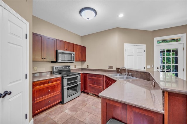 kitchen with a peninsula, light stone countertops, a sink, appliances with stainless steel finishes, and light tile patterned floors