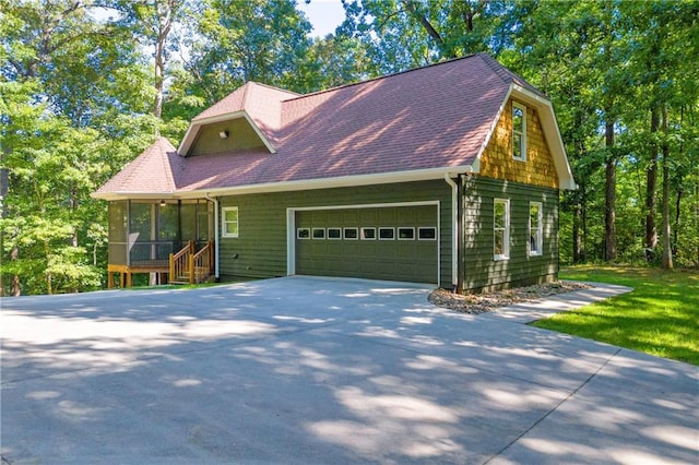 view of front facade featuring an attached garage, roof with shingles, driveway, and a sunroom