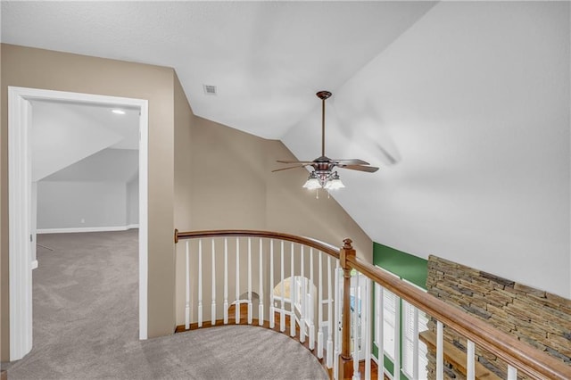 staircase with ceiling fan, vaulted ceiling, and carpet flooring