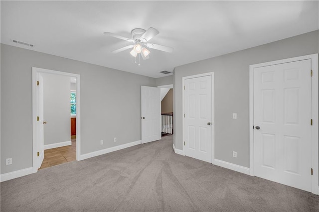 unfurnished bedroom featuring carpet floors, baseboards, connected bathroom, and visible vents