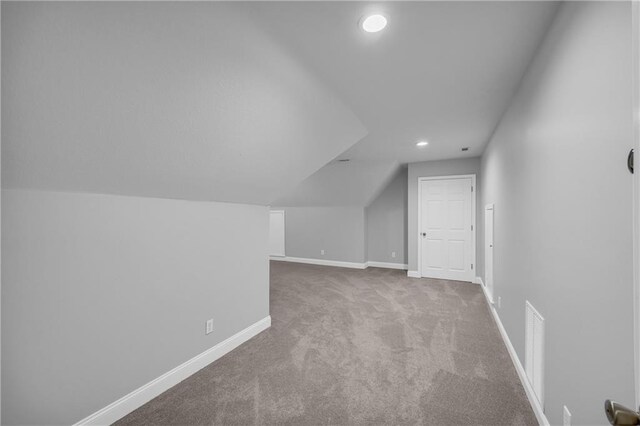 additional living space featuring visible vents, vaulted ceiling, baseboards, carpet flooring, and recessed lighting