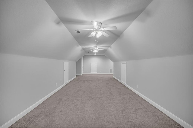 additional living space featuring a ceiling fan, visible vents, vaulted ceiling, carpet floors, and baseboards
