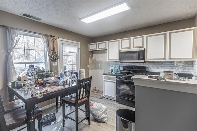 kitchen featuring backsplash, a textured ceiling, white cabinets, and black gas stove