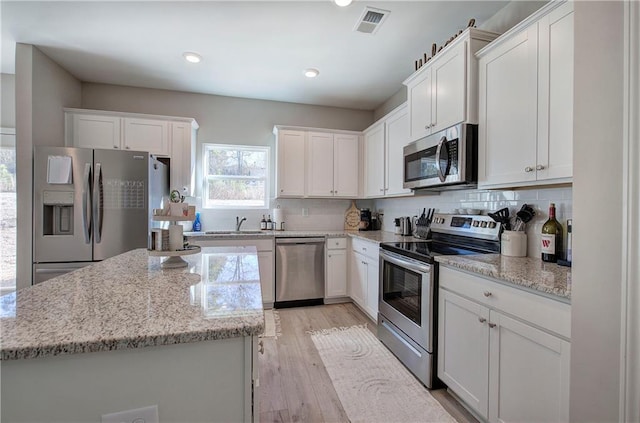 kitchen with appliances with stainless steel finishes, white cabinets, and light stone counters