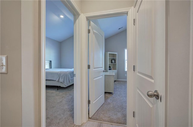 corridor with light carpet and vaulted ceiling