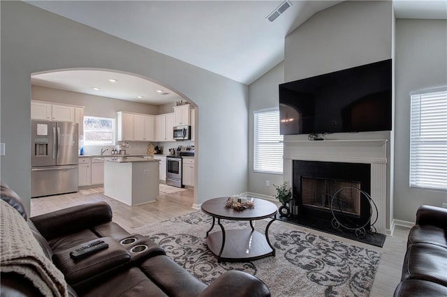 living room with plenty of natural light, lofted ceiling, and light wood-type flooring