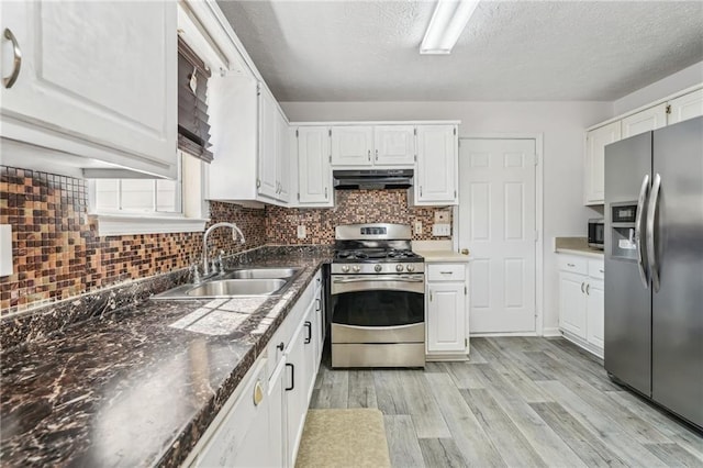 kitchen with white cabinets, light wood-style flooring, appliances with stainless steel finishes, under cabinet range hood, and a sink