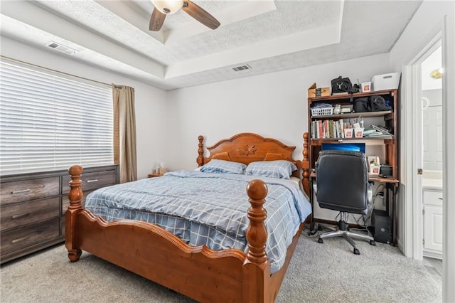 bedroom with visible vents, ceiling fan, a tray ceiling, a textured ceiling, and carpet flooring