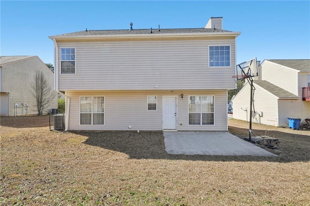 rear view of house with central air condition unit, a yard, a chimney, and a patio