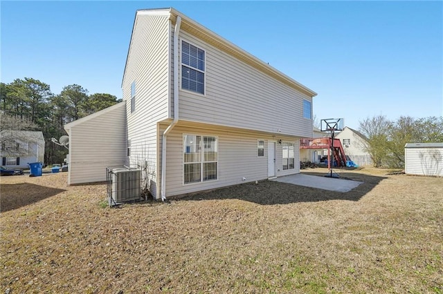 rear view of property with a patio, a lawn, central AC, and an outbuilding