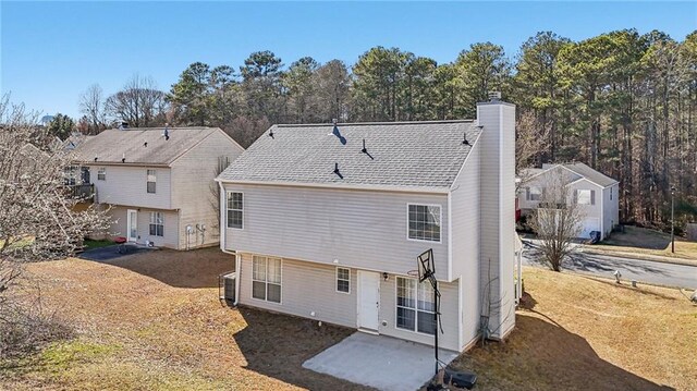 back of property with central AC, roof with shingles, and a chimney