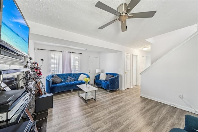 living room with a textured ceiling, wood finished floors, and baseboards