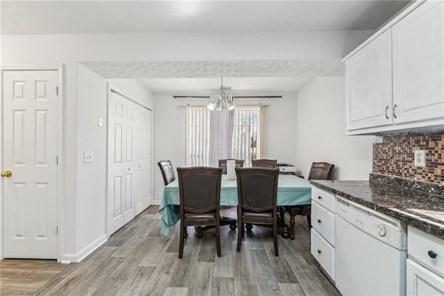 dining room featuring baseboards, light wood finished floors, and a notable chandelier