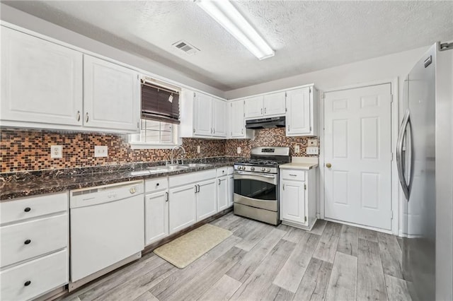 kitchen with appliances with stainless steel finishes, light wood-type flooring, under cabinet range hood, white cabinetry, and a sink