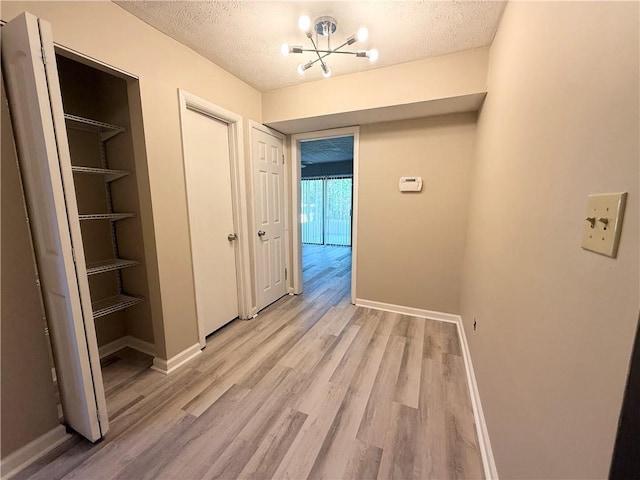 296 Country Club Dr, Jonesboro, GA 30238 - corridor featuring light wood-type flooring, a textured ceiling, baseboards, and a chandelier