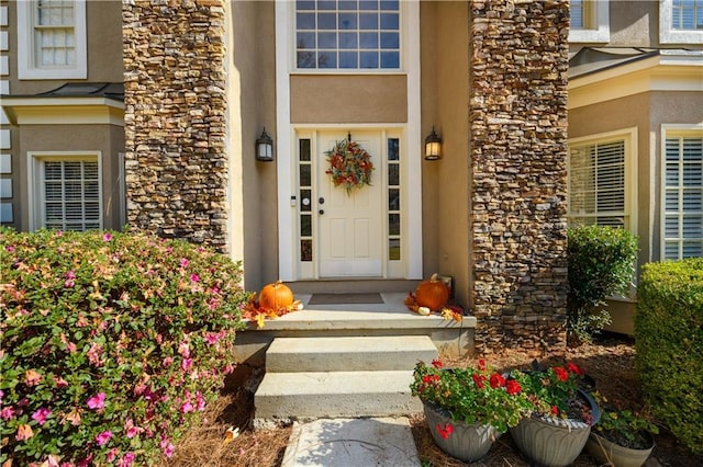 view of exterior entry featuring stone siding and stucco siding