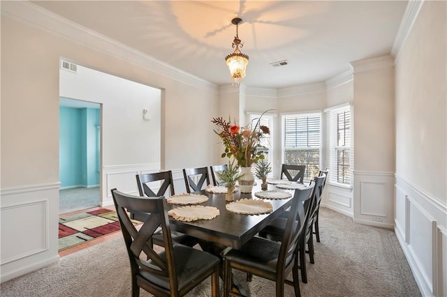 carpeted dining area featuring ornamental molding and a chandelier