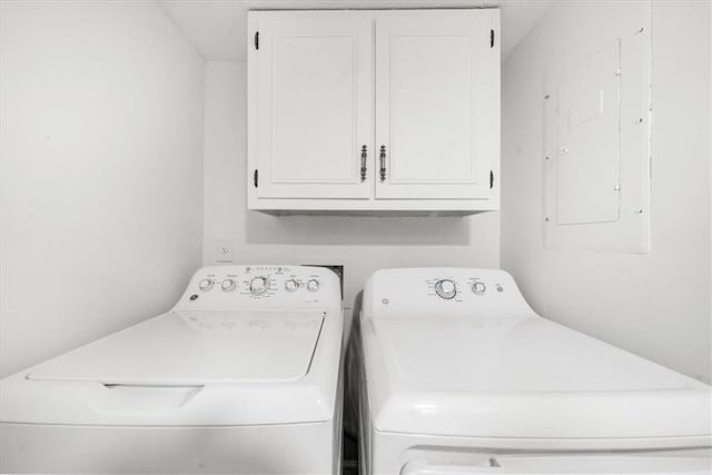 washroom featuring cabinets, washing machine and clothes dryer, and electric panel