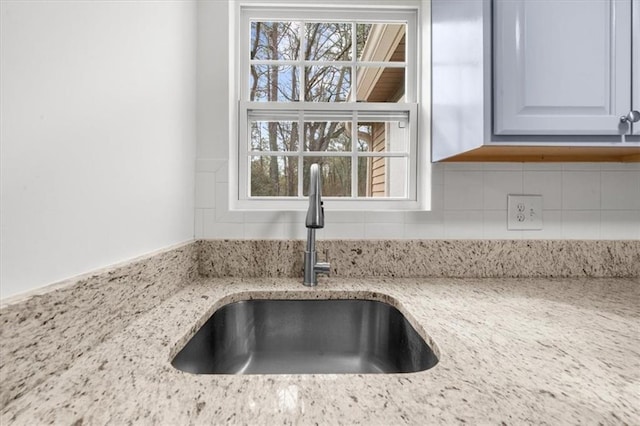 details with light stone counters, sink, and backsplash