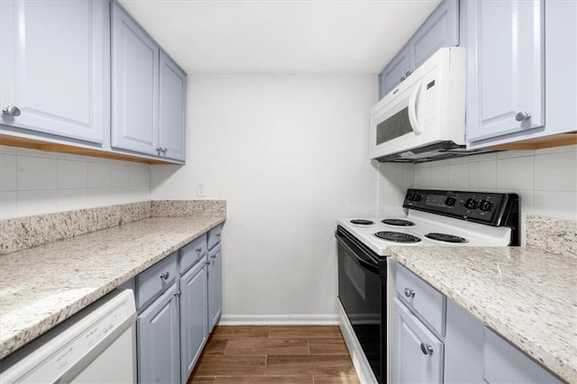 kitchen with tasteful backsplash, light stone counters, and white appliances