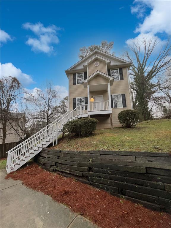 view of front of home featuring stairway and a front yard