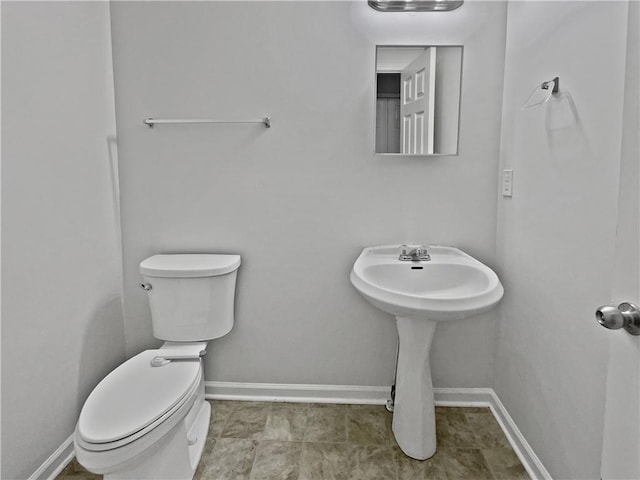 half bathroom with baseboards and toilet