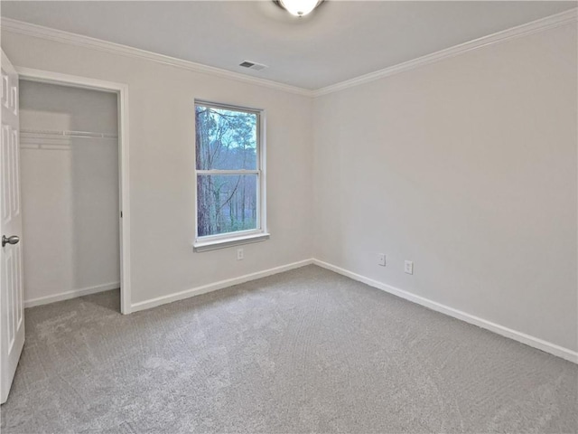 unfurnished bedroom with a closet, visible vents, crown molding, and carpet