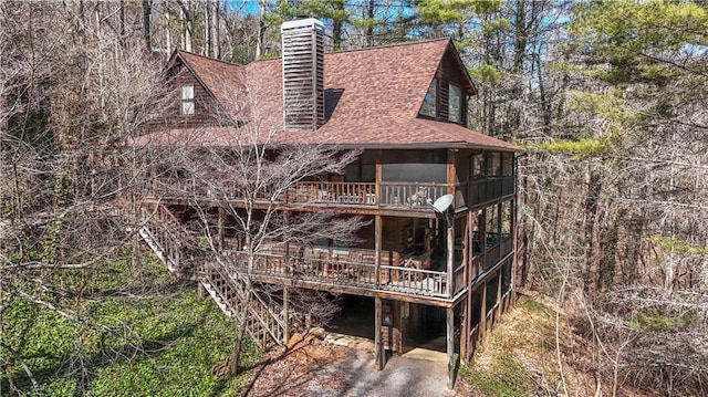 exterior space with a deck, a shingled roof, and a chimney