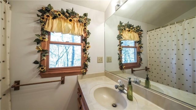 full bath with lofted ceiling, vanity, and a healthy amount of sunlight