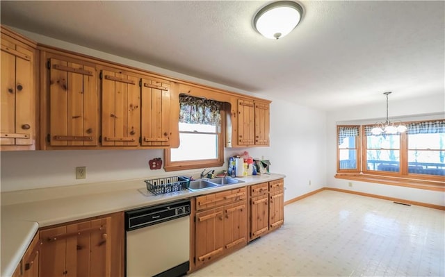 kitchen featuring a sink, baseboards, light countertops, dishwasher, and pendant lighting