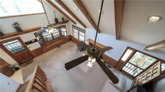 carpeted living room with ceiling fan, high vaulted ceiling, and beam ceiling