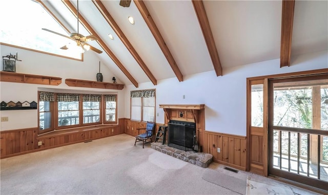 living area with carpet floors, wainscoting, beam ceiling, and a healthy amount of sunlight