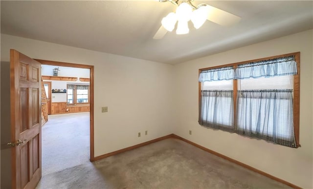 unfurnished room with baseboards, a ceiling fan, and light colored carpet