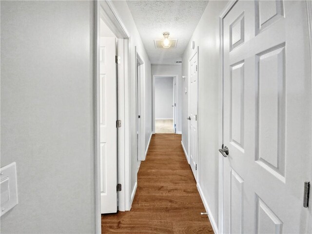 hallway featuring a textured ceiling and dark hardwood / wood-style floors