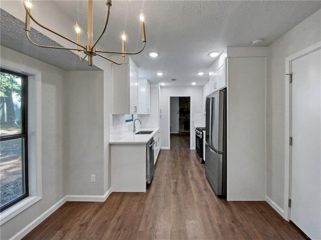 kitchen featuring sink, dark wood-type flooring, a textured ceiling, white cabinets, and appliances with stainless steel finishes