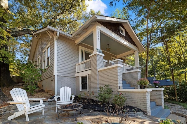 rear view of house featuring a fire pit, a balcony, and a patio area