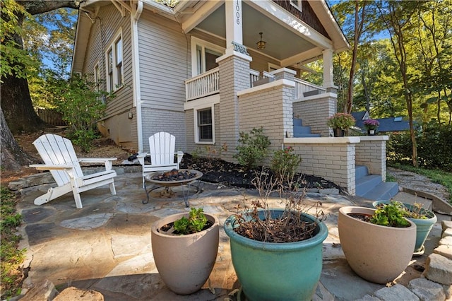 view of patio featuring a fire pit and a balcony